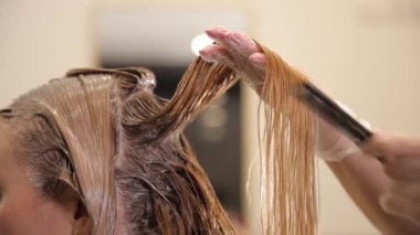 Kuaför, bir kadın saçına bir güzellik salonundaki fırçayla boya uygular. Yakın plan saç telleri.. 
