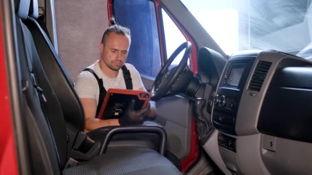 一个男人坐在汽车的司机座位上 边停车边看书 这辆车似乎是一辆卡车 — 图库视频影像