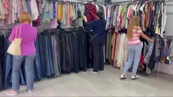 三位女士浏览了一家服装店 探索袖子长度 紫罗兰色 洋红色调 T恤衫 时装设计 大腿长度选择 运动服和斜纹棉布 — 图库视频影像