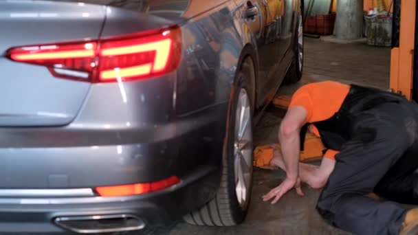 一名男子正在车库里检查汽车轮胎和合金轮 同时检查尾灯和刹车灯是否出了问题 — 图库视频影像