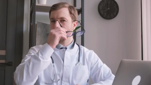 Ένας Γιατρός Πουκάμισο Κάθεται Ένα Γραφείο Προσαρμόζοντας Γυαλιά Του Ενώ — Αρχείο Βίντεο