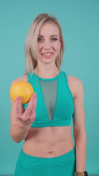 一个手里拿着柠檬的女人穿着绿色上衣 展示着她的胳膊 肩膀和腹部 — 图库视频影像