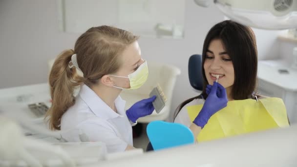 一名戴着眼镜的妇女坐在牙椅上 而牙医则在检查她的牙齿 她在休闲活动中兴高采烈地微笑着 — 图库视频影像
