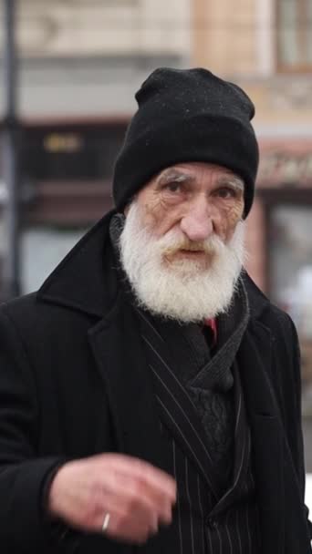 バーティカルビデオ 古い灰色の髪の祖父の肖像画は 屋外に立っている黒い服を描き 指の指を振った 冬の路上で祖父に警告する 危険のジェスチャー — ストック動画