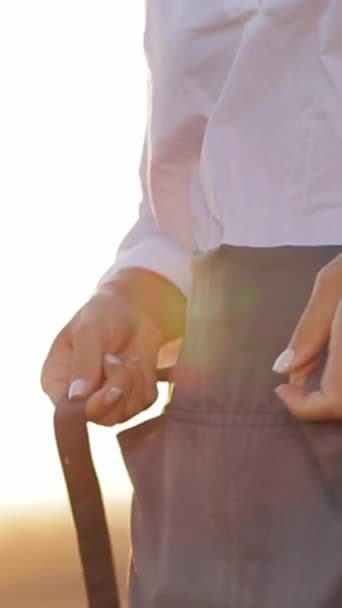 一个女人站在硬木地板上 用她的大拇指和手腕做着一个动作 用她的大腿把物体塞入口袋 — 图库视频影像