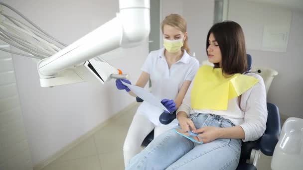 Woman Seated Dental Chair Converses Dentist While Her Thumb Gently — Stock Video