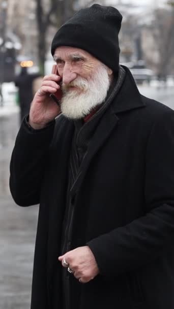 Yaşlı Bir Adamın Kışın Dışarıda Dikilirken Telefonla Konuşmasının Dikey Video — Stok video