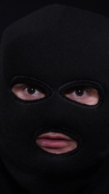 Siyah kar maskesi takan, gözle görülür kirpikleri, çene çizgileri ve karanlıkta kırışıklıkları olan birinin detaylı bir fotoğrafı..