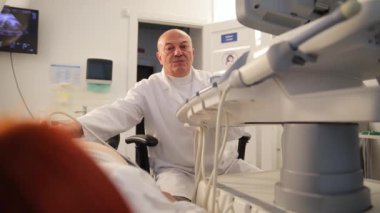 Bir tıp uzmanı muayene odasında bir hastaya ultrasonla ultrason çekiyor.