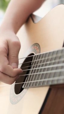 Birilerinin gitar, müzik aleti ve gitar telleri ve parmak hareketleriyle çalınan tellerin detaylı bir görüntüsü..