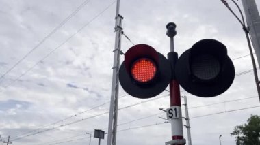 Bulutlarla kaplı bulutlu bir günde kırmızı bir demiryolu ışığı, bir sinyal cihazı..