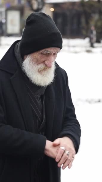 老人は外の寒さから手をこすります 雪の背景に冬の老人の肖像画 — ストック動画
