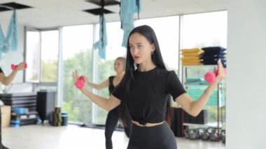Spor salonundaki bir grup kadın halterlerini kaldırıyor, kollarını güçlendiriyor, kolları ve başparmakları ağırlıkları kavrıyor..
