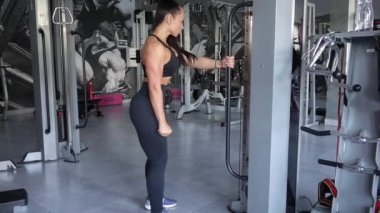 Genç ve seksi bir kadın spor salonundaki modern egzersiz makinesinde çalışıyor. Sporcu kadın simülatörle bacak egzersizi yapıyor..