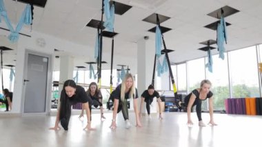 Spor salonunda bir grup kadının ahşap zeminde hava yogasından zevk aldığı eğlenceli bir etkinlik..