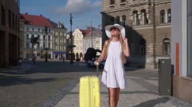 Beyaz elbiseli zarif genç turist kadın güneşli bir yaz gününde şehre bakıyor. Avrupa 'da dinlen.