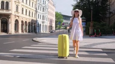 Güzel, ince, iyi giyimli, sarı bavullu bir turist bir Avrupa şehrinde caddeyi geçiyor. Avrupa 'da Hafta Sonu