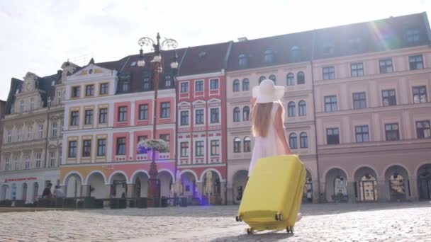 Egy Karcsú Szőke Fehér Kalapban Sétál Városközponton Egy Sárga Bőrönddel — Stock videók