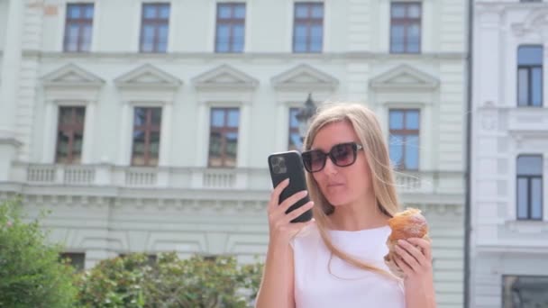 Uma Menina Bonita Com Cabelo Comprido Está Comendo Donut Olhando — Vídeo de Stock