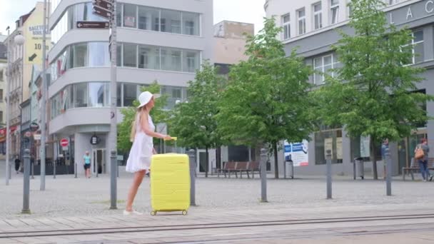 大都市のスーツケースを持った女性 メトロポリスの黄色いスーツケースを持つ若い観光客 — ストック動画