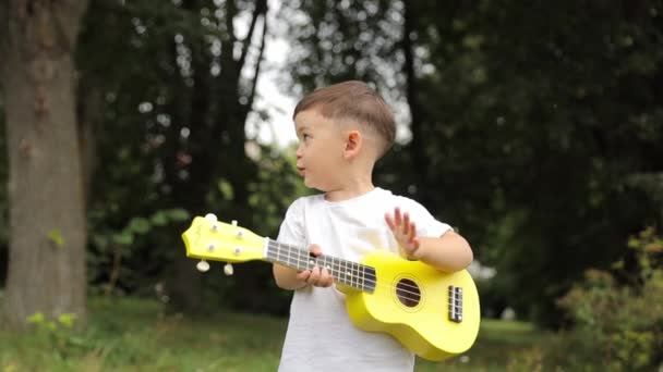 Barnmusiker Spelar Gärna Den Gula Ukulelen Gräset Parken Och Gör — Stockvideo