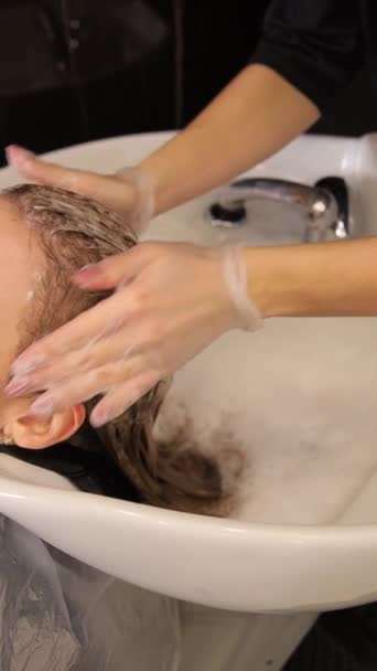 一位女士正在一家理发店用她们的手把洗发水按摩到她的头皮上 美发师正在给她洗头 — 图库视频影像
