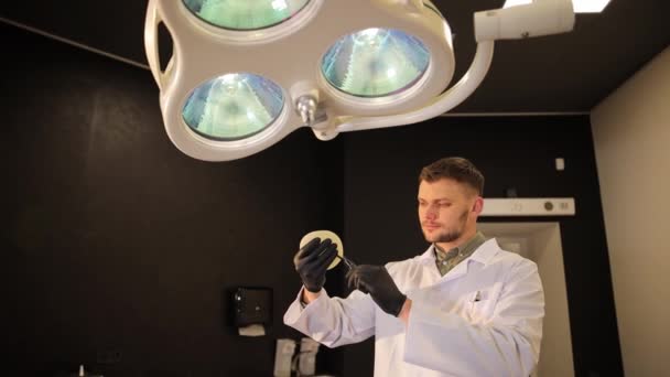 성형외과의사는 수술실에 실리콘 임플란트를 램프의 배경에 맞서고 있습니다 — 비디오