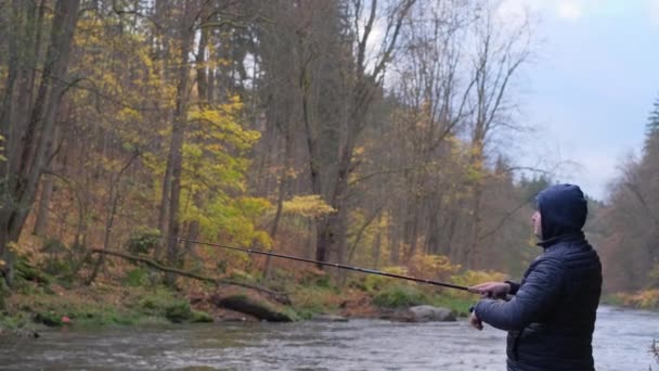 一个人在河里钓鱼时钓到了鱼 拉起了钓竿 渔夫拿着钓竿 在河岸上纺着一条钓丝 在河边钓梭鱼 — 图库视频影像