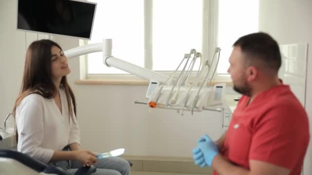 ポジティブで楽しい歯科医と女性患者が歯科オフィスで話しています 歯医者コンサルティング 歯医者の予約で美しい患者さん — ストック動画