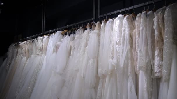 许多白色婚纱挂在婚纱沙龙的衣架上 漂亮的白色婚纱在等着新娘 — 图库视频影像