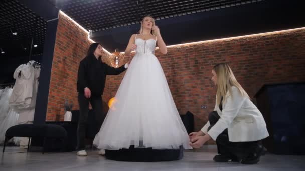 Twee Vrouwelijke Adviseurs Helpen Een Bruid Kleden Een Bruidssalon Een — Stockvideo