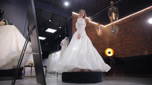 Счастливая Высокая Блондинка Невеста Примеряет Белое Платье Кружась Свадебном Салоне — стоковое видео