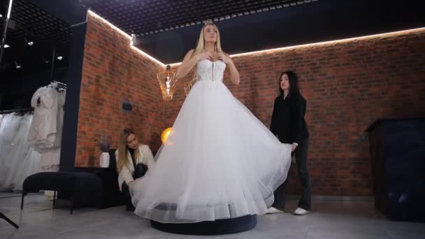 Elegancka Blondynka Przymierzająca Suknię Ślubną Butiku Ślubnym Konsultanci Sprzedaży Pomagają — Wideo stockowe