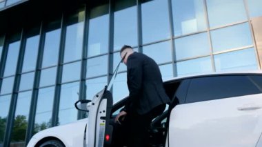 Takım elbiseli bir işadamı, şehirdeki cam bir binanın yakınındaki beyaz bir arabayla yola çıkıyor. Şirketin başı. Zengin bir adam.