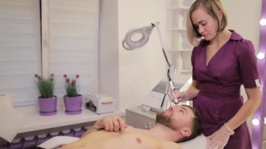 Bir kadın göğsünü incelerken, güzellik salonunda erkekler için yüz ve lazer tedavisi ile rahatlayın. Canlandırıcı hizmetlerle kendinizi şımartın ve tazelenmiş hissederek ayrılın.