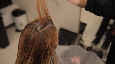 Bir kuaför, kuaförde orta yaşlı bir kadın için sarı saçların köklerini fırçayla boyuyor. Güzellik konsepti