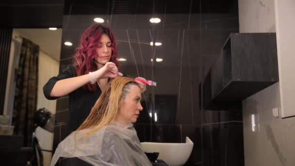 미용사는 미용실에서 여성용 브러시로 머리카락의 뿌리를 그립니다 아름다움 — 비디오