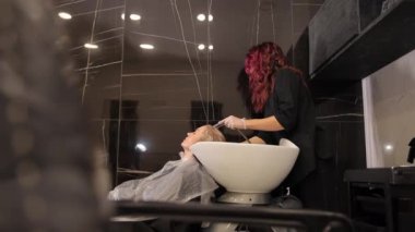 Kuaför kız kuaförde bir kadının kafasını yıkıyor. Güzellik salonunda kafanı profesyonel saç ürünleriyle yıkamak.