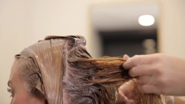 Bir kadın saçına fırçayla boya süren bir kuaförün yakın çekimi. Profesyonel amonyaksız boyalarla saç boyası..