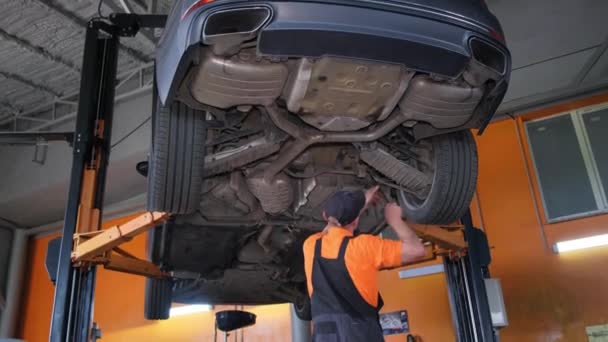 Hombre Está Trabajando Neumático Automotriz Debajo Coche Ascensor Garaje Rodeado — Vídeo de stock