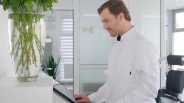 Resmi kıyafet giyen bir bilim adamı laboratuvar ortamında tablet bilgisayar kullanıyor.