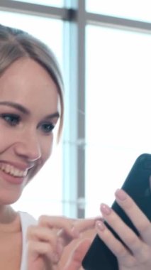 Bir kadın cep telefonuna bakarken gülümsüyor. Yüksek kalite