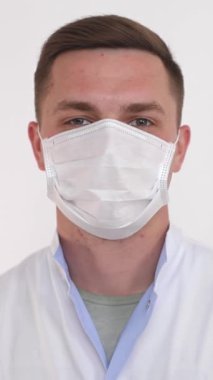 Alnını, kaşlarını, kirpiklerini, çenesini ve insan vücudunu korumak için yüzüne beyaz bir tıbbi maske takan bir adam.