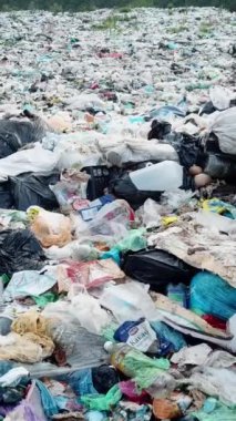 Bir tepenin tepesinde manzarayı kirleten bir yığın plastik atık görülüyor. Sıvı atık toprağa sızar ve elektrik mavisi bir aksesuarla zararlı bir olay yaratır.