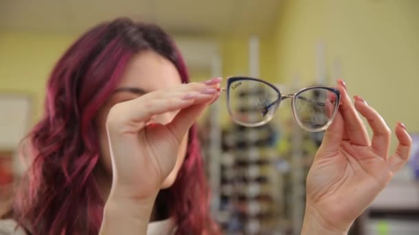 Ein Mädchen Mit Schönen Roten Lockigen Haaren Wählt Eine Brille — Stockvideo