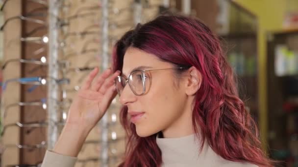 Una Joven Chica Aspecto Americano Elige Gafas Borde Oscuro Mientras — Vídeo de stock