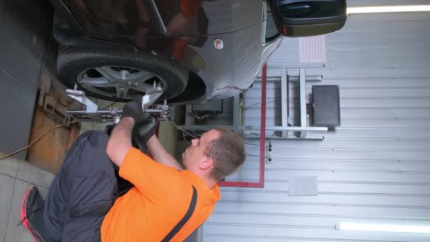 一名男子正在修理车库里的一辆汽车 正在更换轮胎和车轮 检查汽车的照明和外部 他正在修理挡泥板和汽车轮系 — 图库视频影像