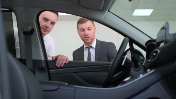 Profesjonalny Młody Konsultant Handlowy Doradza Młodemu Człowiekowi Przy Zakupie Samochodu — Wideo stockowe