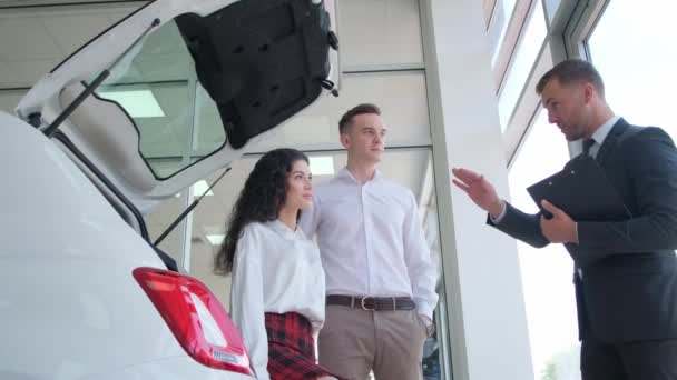 一对年轻夫妇在一家汽车经销店买了一辆新车 一个成功的汽车购买交易 买方与销售经理握手 — 图库视频影像