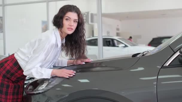 매력적인 어두운 여자는 새로운 카메라에 자동차의 후드에 기대고 비디오 아름다운 — 비디오